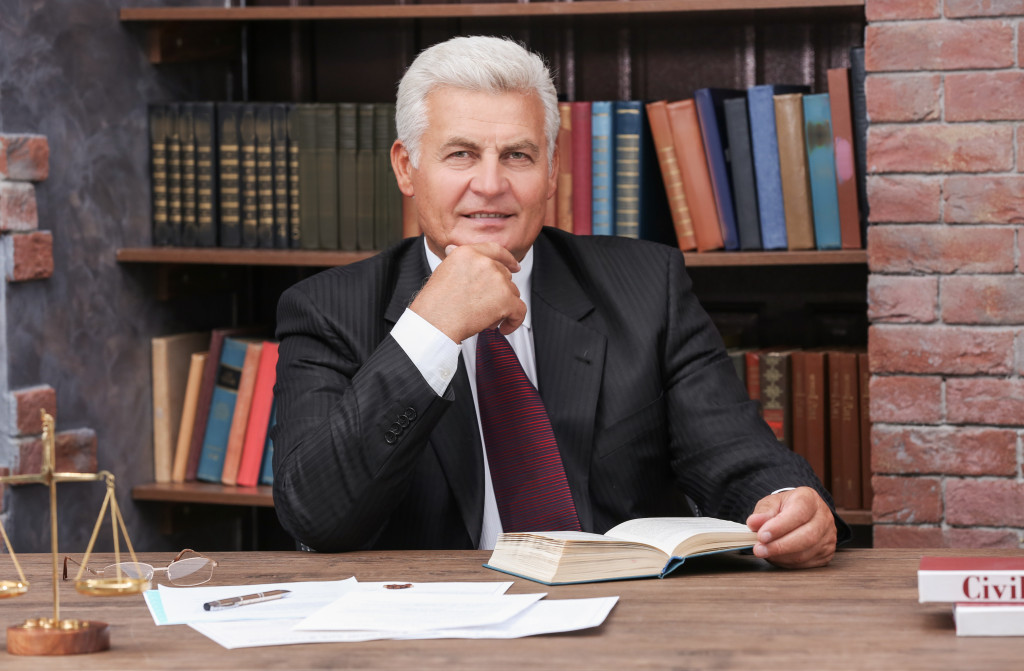 A technology patent lawyer looking at the camera while holding a book in his office