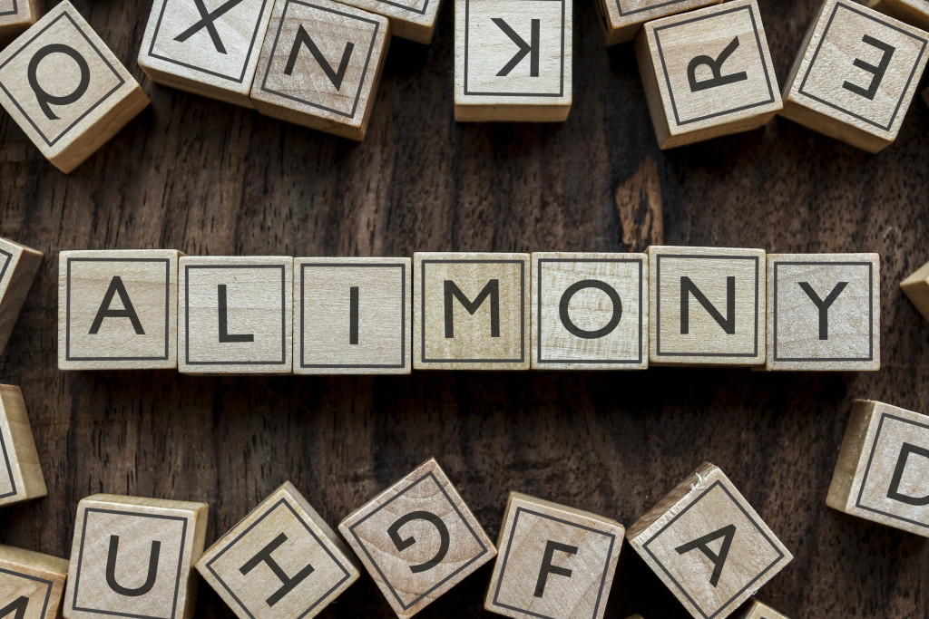 word blocks spelling alimony with wood background